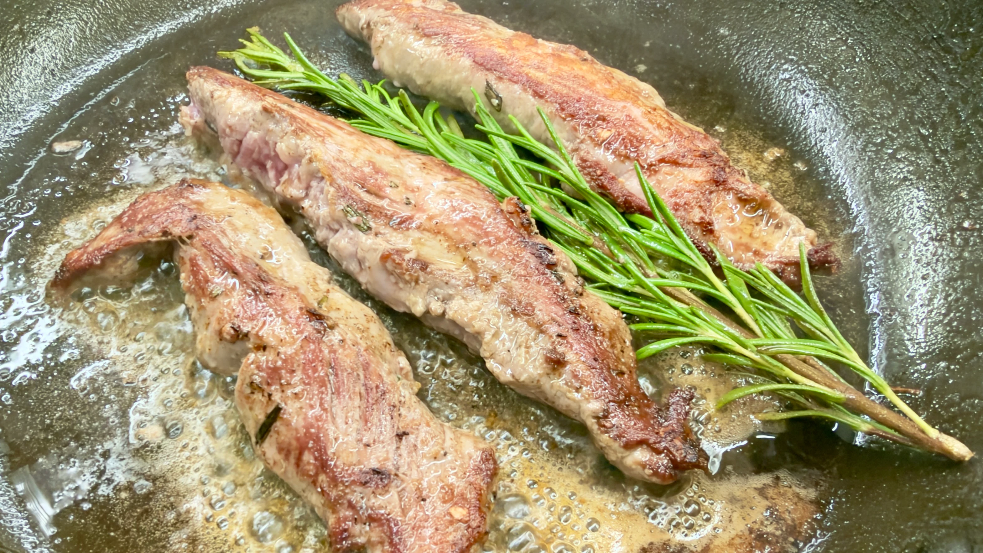 Gebratenes Fleisch mit Rosmarin in einer Pfanne